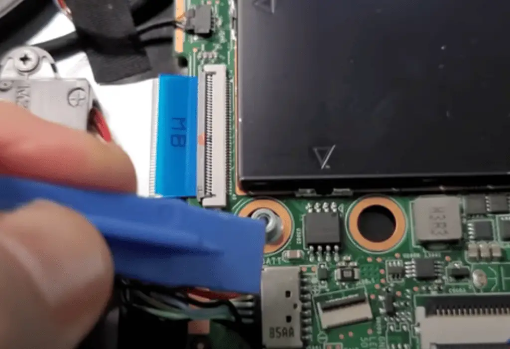 Use a plastic tool to disconnect the battery from the motherboard